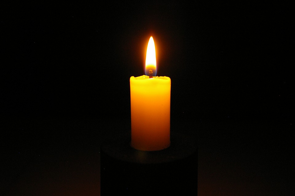 This is an image of a yellow candle burning in a dark setting.